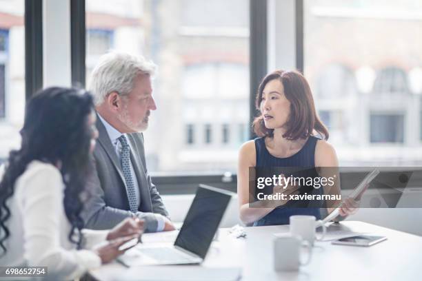 geschäftsfrau mit kollegen diskutieren im büro - multi ethnic business people having discussion at table in board room stock-fotos und bilder