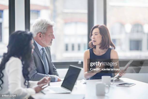 businesswoman discussing with colleagues in office - three people at table stock pictures, royalty-free photos & images