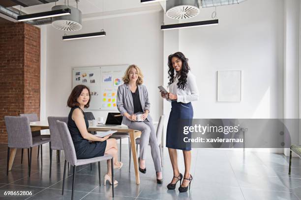 portrait of smiling businesswomen at board room - three people stock pictures, royalty-free photos & images