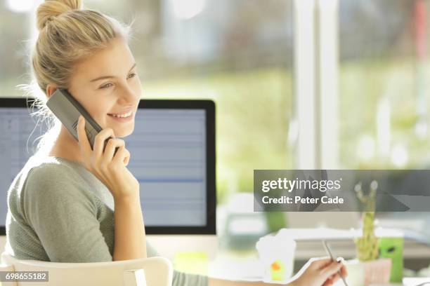 woman sat in modern office talking on phone - festnetztelefon stock-fotos und bilder