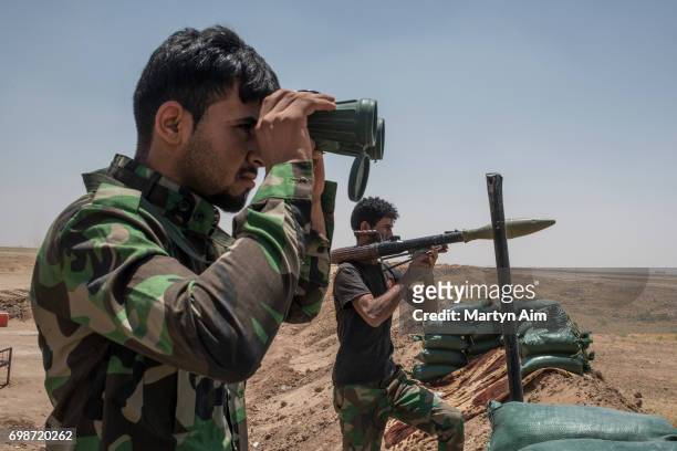 An Iraqi PMF fighter looks through binoculars June 20, 2017 on the Iraq-Syria border in Nineveh, Iraq. The Popular Mobilisation Front forces,...