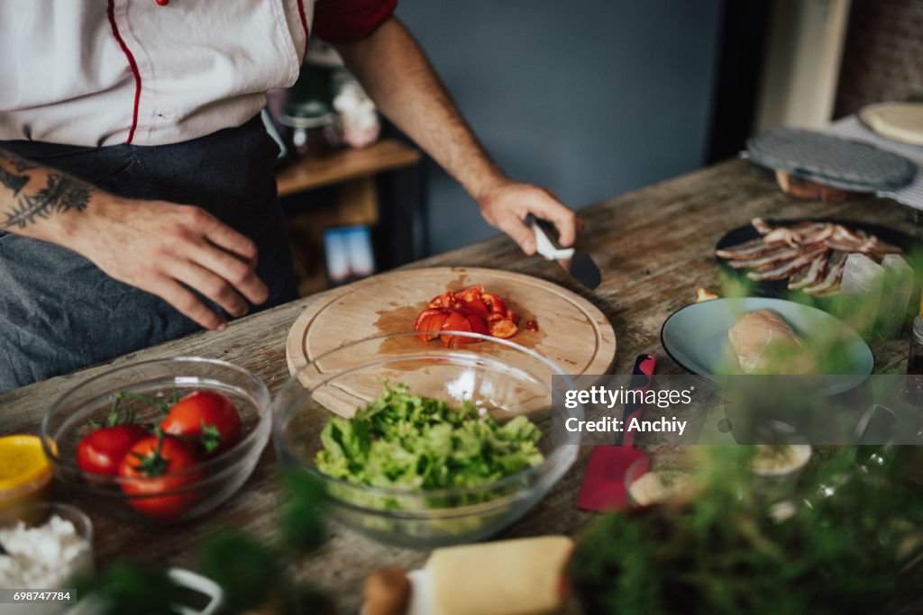 Chef has finished chopping tomato into pieces for the salad