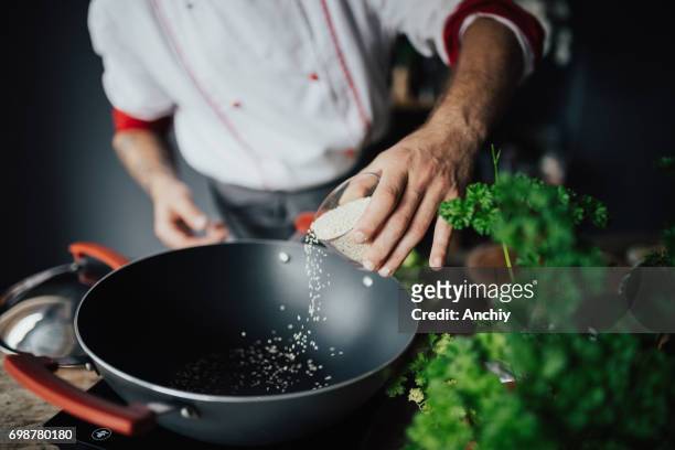 the chef is pouring sesame into hot pan - chef demonstration stock pictures, royalty-free photos & images