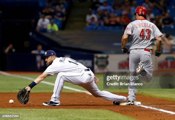 Scott Schebler of the Cincinnati Reds reaches first base on an infield single ahead of first baseman Trevor Plouffe of the Tampa Bay Rays during the...