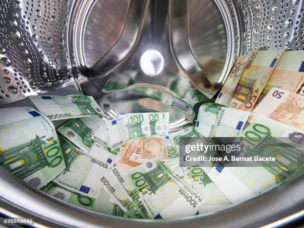 various paper currencies from 100 and 50 euros inside a washing machine - money laundering foto e immagini stock