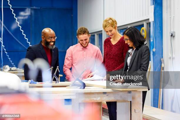 happy business team discussing while standing in factory - contract manufacturing stock pictures, royalty-free photos & images