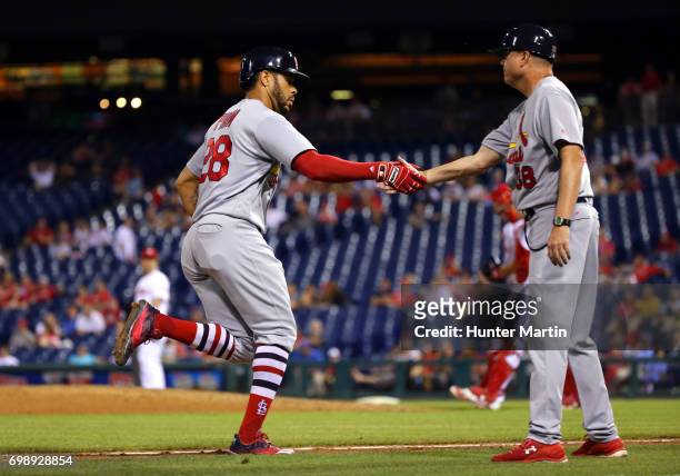 Tommy Pham of the St. Louis Cardinals is congratulated by third base coach Mike Shildt after hitting a two-run home run in the 11th inning during a...