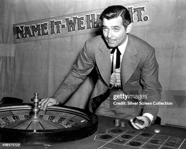 American actor Clark Gable as con man Candy Johnson in the western 'Honky Tonk', 1941. A sign behind him reads 'Name it - We Have it'.