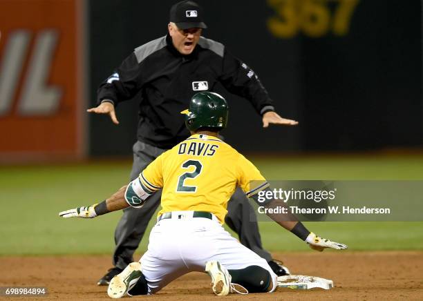 Khris Davis of the Oakland Athletics signals safe with second base umpire Mike Everitt after Davis dove into second with a double against the Houston...