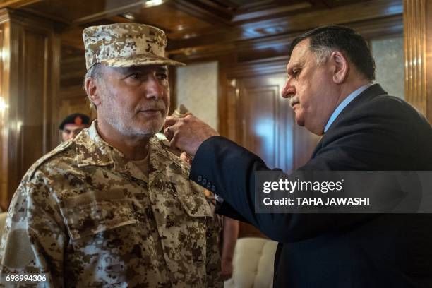 Libyan unity government's Prime Minister Fayez al-Sarraj presents Colonel Osama Jueily with the rank of higher military commander of the Libyan army...