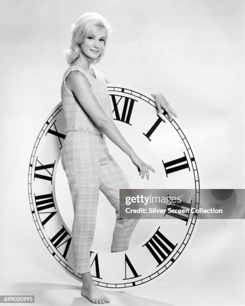 American actress Yvette Mimieux poses by a large clock, circa 1960. She starred as Weena in the 1960 science fiction film 'The Time Machine'.