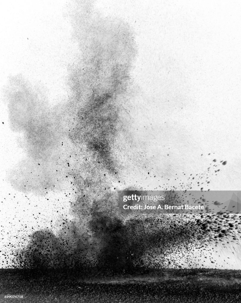 Explosion of a cloud of powder of particles of colors gray and black and a white background