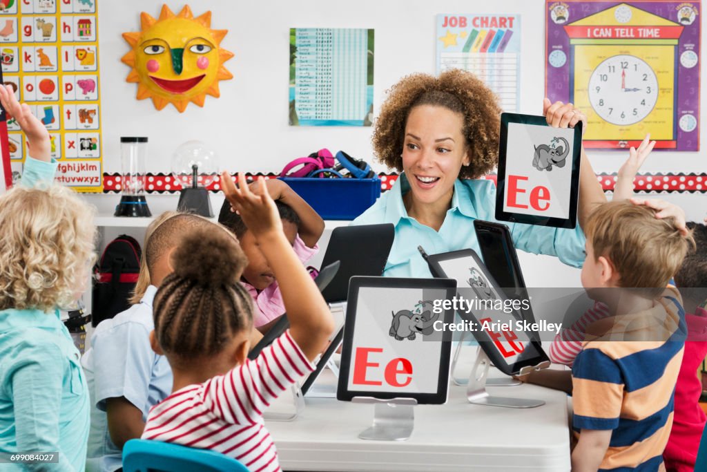 Teacher and students learning alphabet with digital tablets