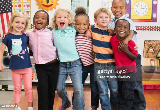 portrait of smiling students hugging in classroom - preschool stock pictures, royalty-free photos & images