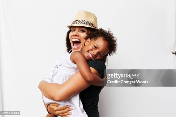 smiling mixed race woman hugging daughter - millennial generation stock-fotos und bilder