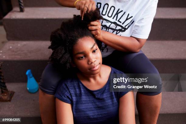 black mother styling hair of daughter on staircase - stoop stock pictures, royalty-free photos & images
