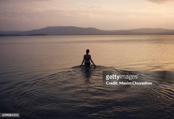 silhouette of caucasian woman wading in lake - 水につかる ストックフォトと画像