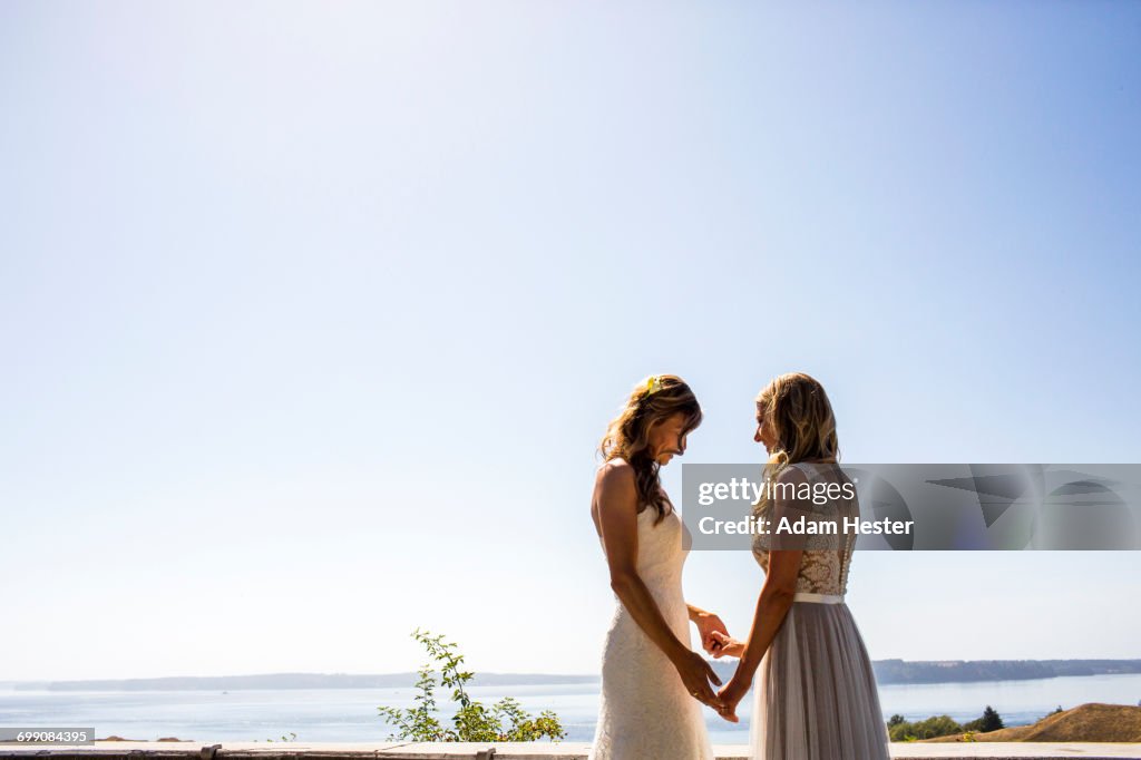 Caucasian brides holding hands at waterfront