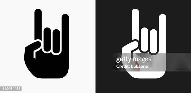 rock and roll hand icon on black and white vector backgrounds - horn sign stock illustrations