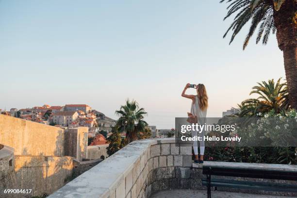 caucasian woman standing on park wall photographing cityscape - tourist camera stock pictures, royalty-free photos & images