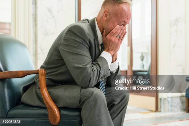 fatigued caucasian politician sitting in armchair rubbing eyes - tensed idaho stock pictures, royalty-free photos & images