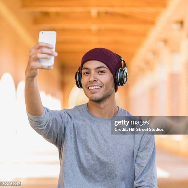 hispanic man wearing headphones posing for cell phone selfie - caldwell idaho stock pictures, royalty-free photos & images
