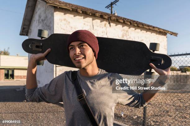 hispanic man carrying skateboard - caldwell idaho stock pictures, royalty-free photos & images
