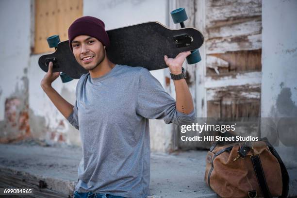 hispanic man holding skateboard - man skating stock pictures, royalty-free photos & images