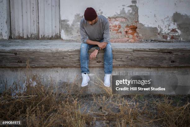 lonely hispanic man sitting on urban wall - tensed idaho stock pictures, royalty-free photos & images