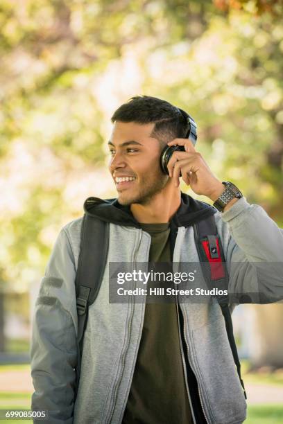 hispanic man carrying backpack listening to headphones - コールドウェル市 ストックフォトと画像