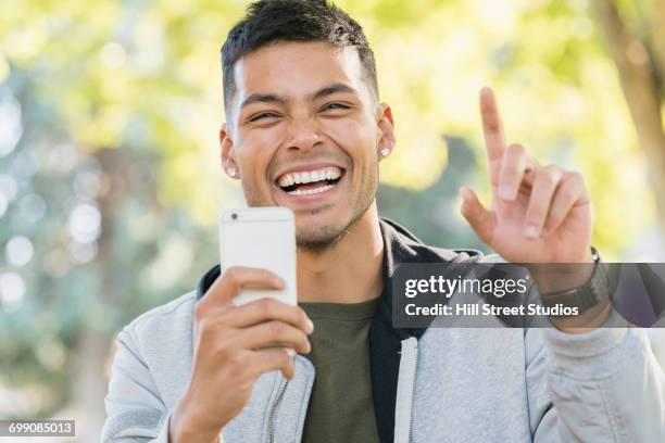 smiling hispanic man posing for cell phone selfie - selfie male stock pictures, royalty-free photos & images