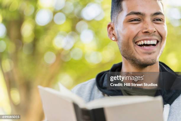 laughing hispanic man reading book - caldwell idaho stockfoto's en -beelden