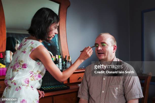 girl applying makeup to eyes of father - kinderschminken stock-fotos und bilder