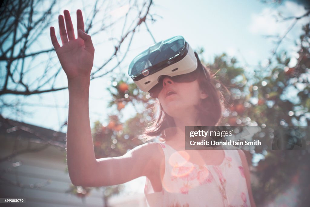 Mixed Race girl using virtual reality goggles outdoors