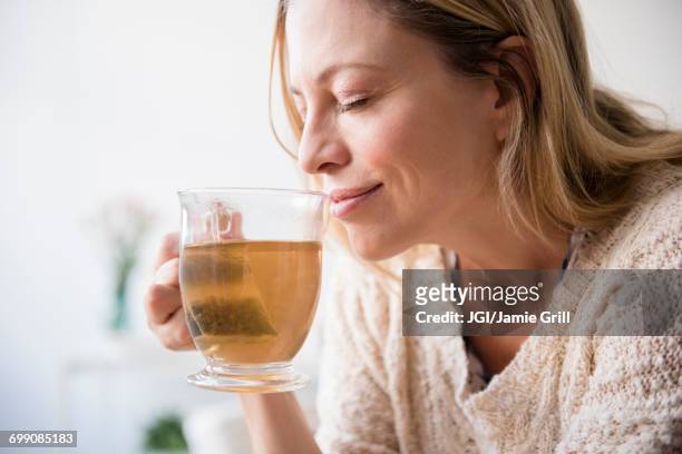 caucasian woman smelling cup of tea - adult woman cup tea stockfoto's en -beelden