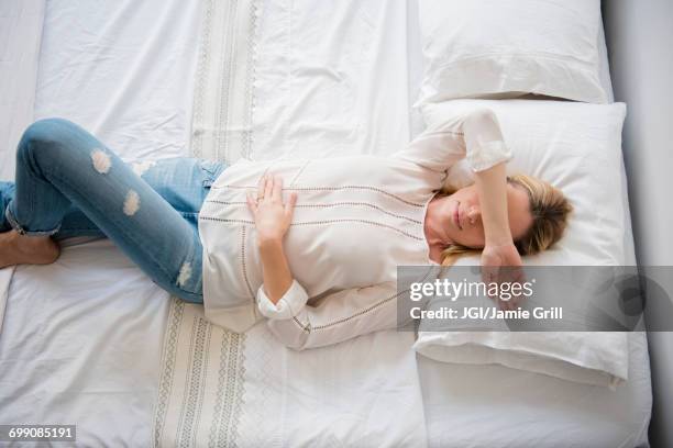 caucasian woman laying on bed covering eyes - woman 45 sleeping stock pictures, royalty-free photos & images