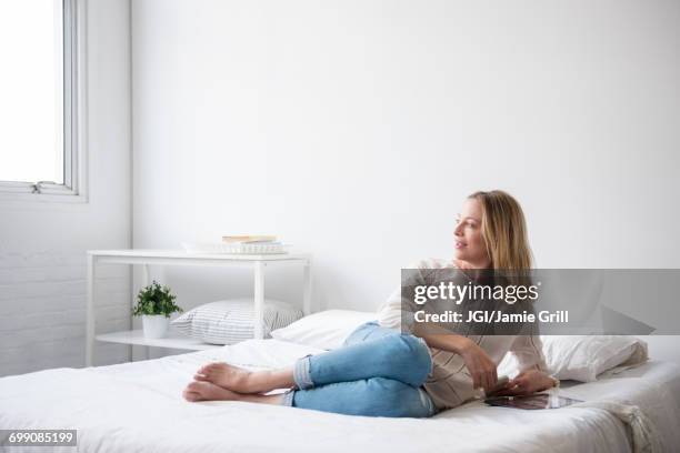 caucasian woman laying on bed looking at window - lying on back ストックフォトと画像