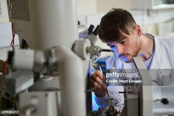 scientists placing object on scientific equipment using tweezers - tweezers stockfoto's en -beelden