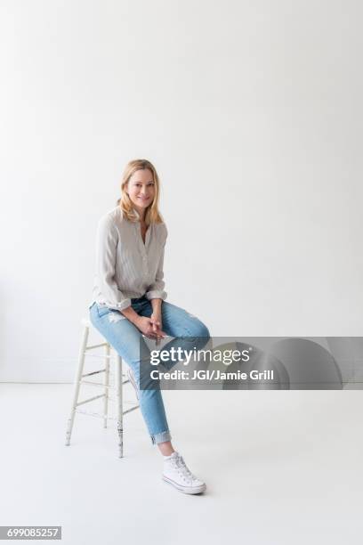 caucasian woman sitting on stool - white jeans fotografías e imágenes de stock