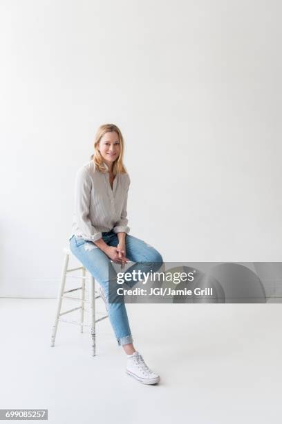 caucasian woman sitting on stool - sgabello foto e immagini stock