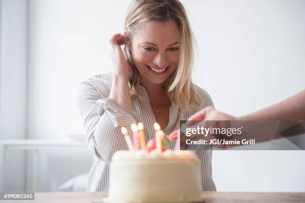 friend lighting candles on birthday cake for caucasian woman - older woman birthday stock pictures, royalty-free photos & images
