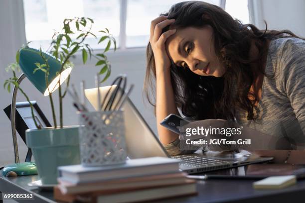 hispanic businesswoman using technology in office - cell phone confused stockfoto's en -beelden