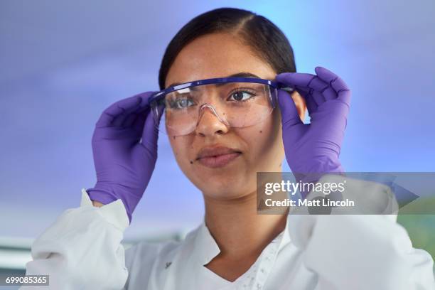 scientist putting on safety glasses - scientist portrait stock pictures, royalty-free photos & images