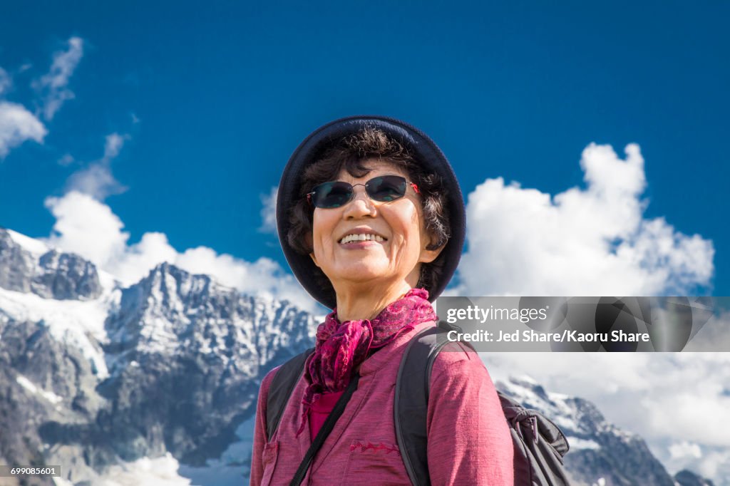 Older Japanese woman smiling near mountain