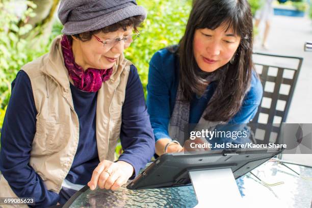 older japanese mother and daughter using digital tablet - kins fotografías e imágenes de stock