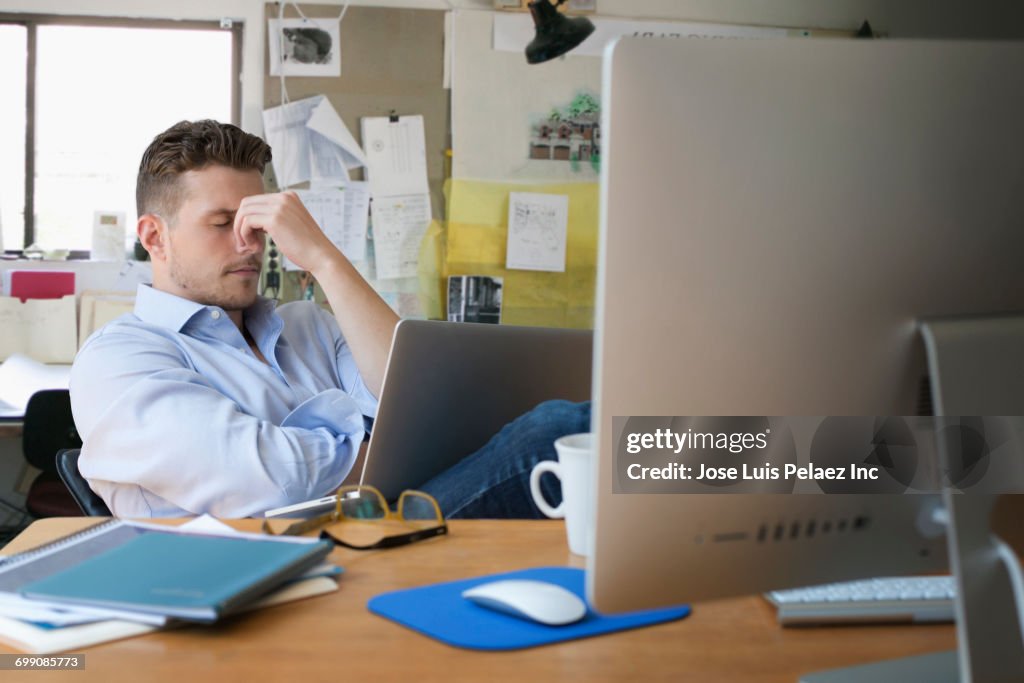 Frustrated Caucasian businessman with laptop in office