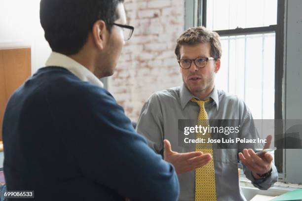 businessmen talking in office - schouders ophalen stockfoto's en -beelden