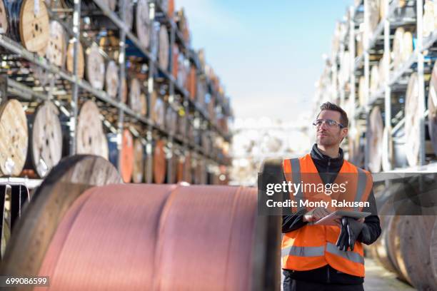 worker inspecting cable reels with digital pad at cable storage facility - cable spool stock pictures, royalty-free photos & images