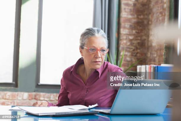 hispanic businesswoman using laptop in office - woman business desk front laptop office fotografías e imágenes de stock