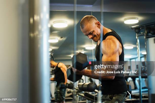 hispanic man weightlifting in gymnasium - muscle building stockfoto's en -beelden